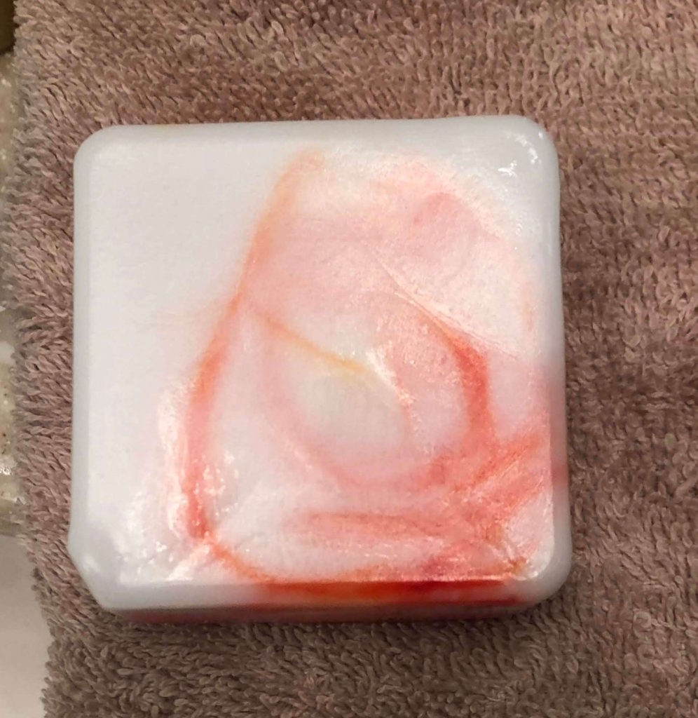 a finished bar of swirled soap rests on a towel
