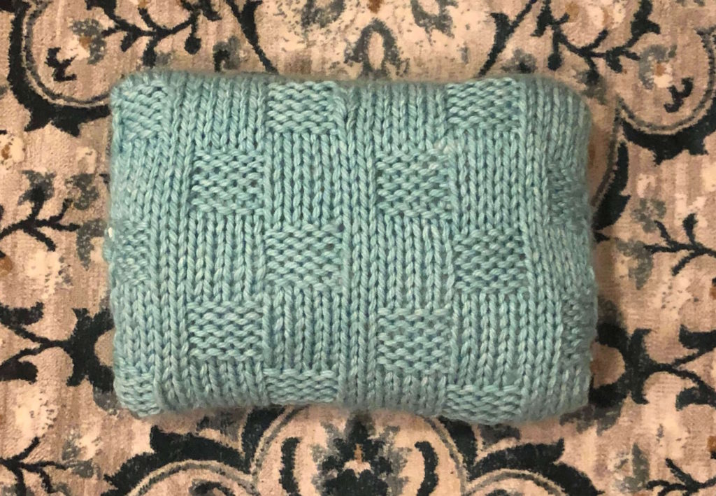 a light blue-green pillow with basketweave stitch