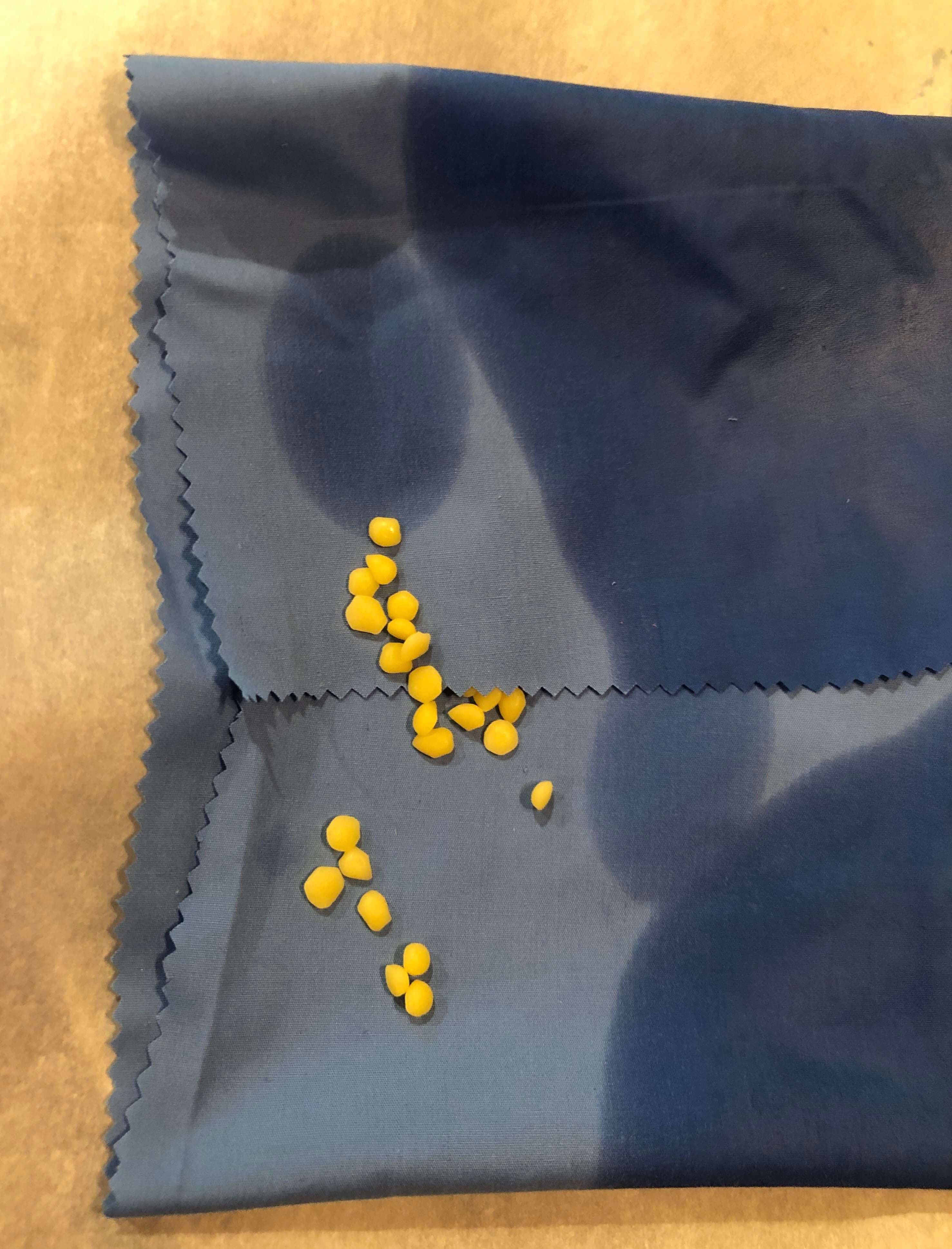 a close-up of the process of adding beeswax pellets to areas of the linen that have not been saturated