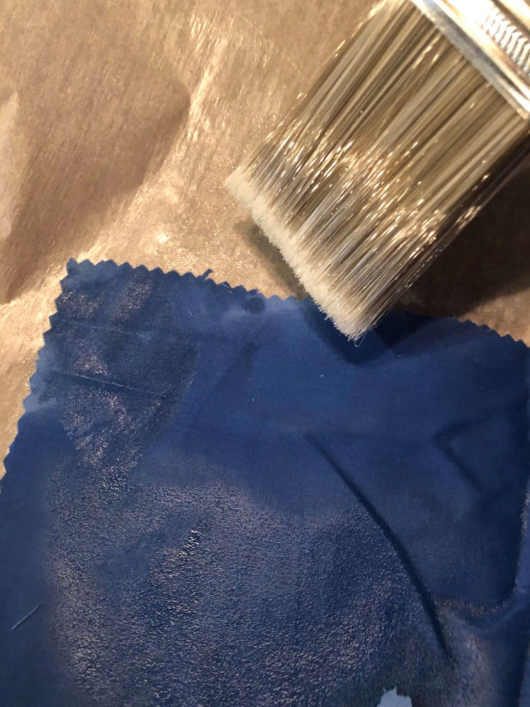 a paintbrush spreads beeswax across the cotton fabric