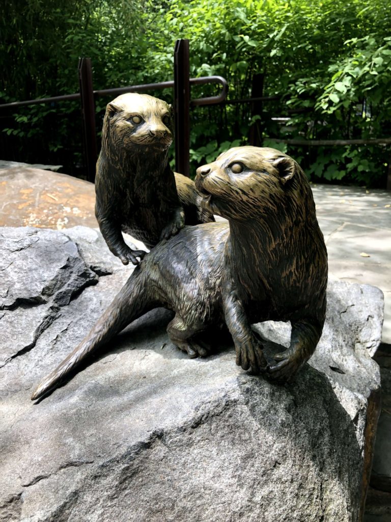 a statue of two otters, grinning playfully at each other