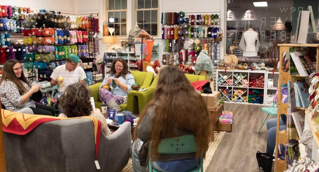 a group of crafters gathers in a room full of yarn