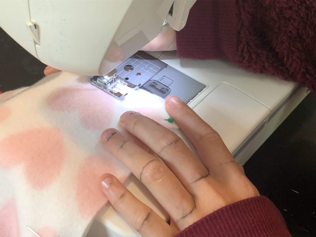 little hands sew fleece together on a sewing machine