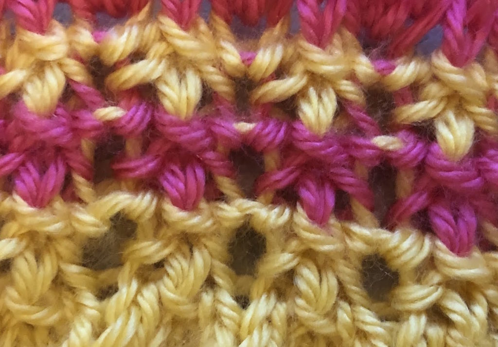 a close-up of the Portcullis knitting stitch worked in watermelon pink and sunshine yellow