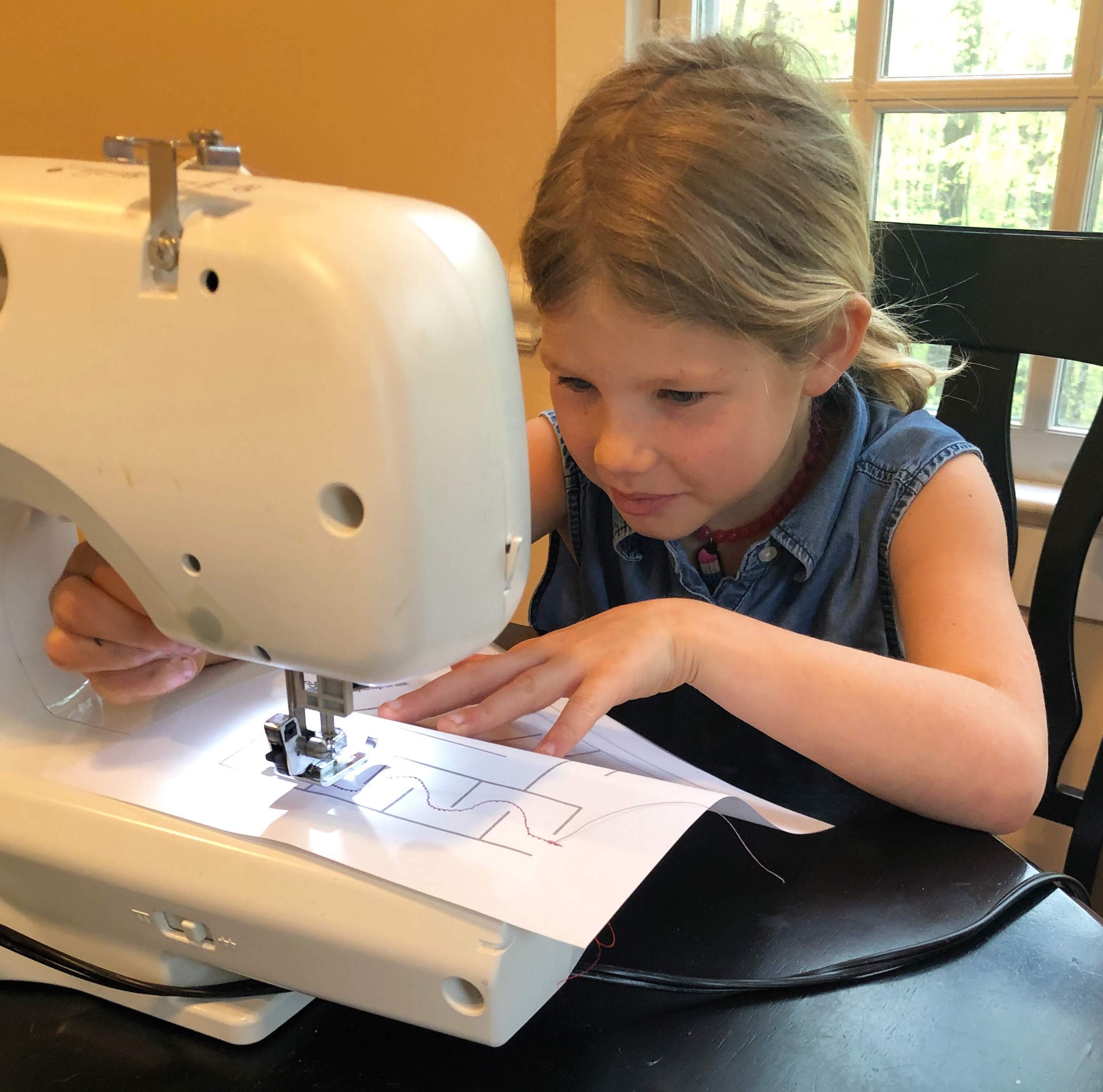 a young girl sewing through a maze on paper