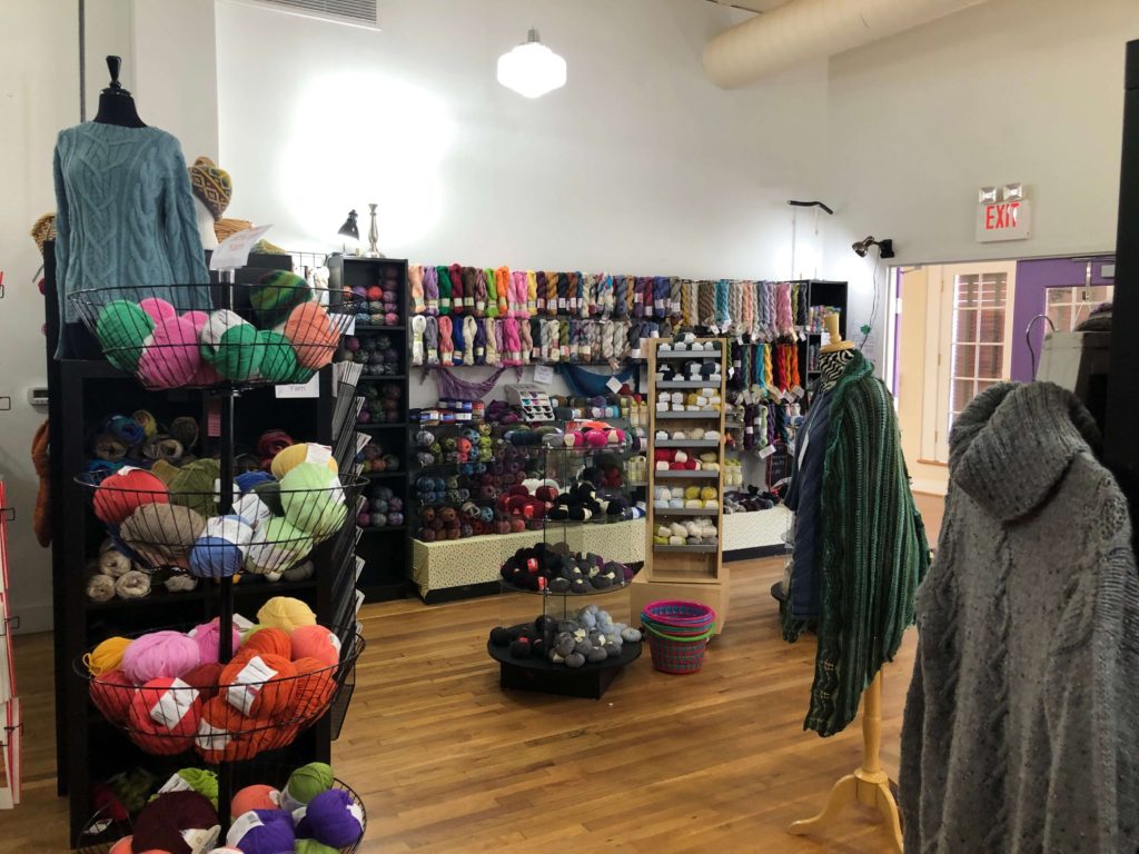 Yarnia of Old Town shop interior: baskets of yarn, finished knits, walls of skeins of yarn