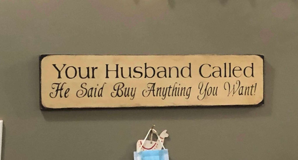 a sign reads "Your Husband Called: He said buy anything you want!"