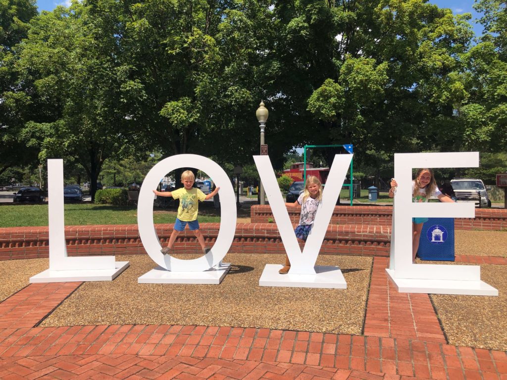 three children pose in the O, V, and E letters of the LOVEworks at the Visitors Center in Front Royal, Virginia