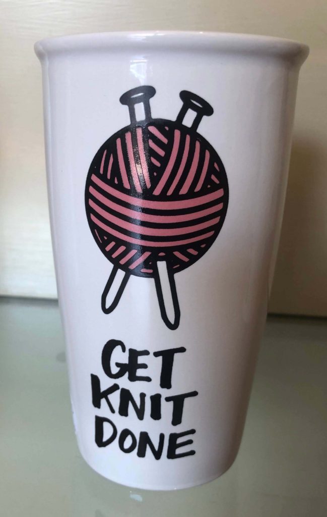 a mug with two knitting needles through a ball of yarn reads "GET KNIT DONE"