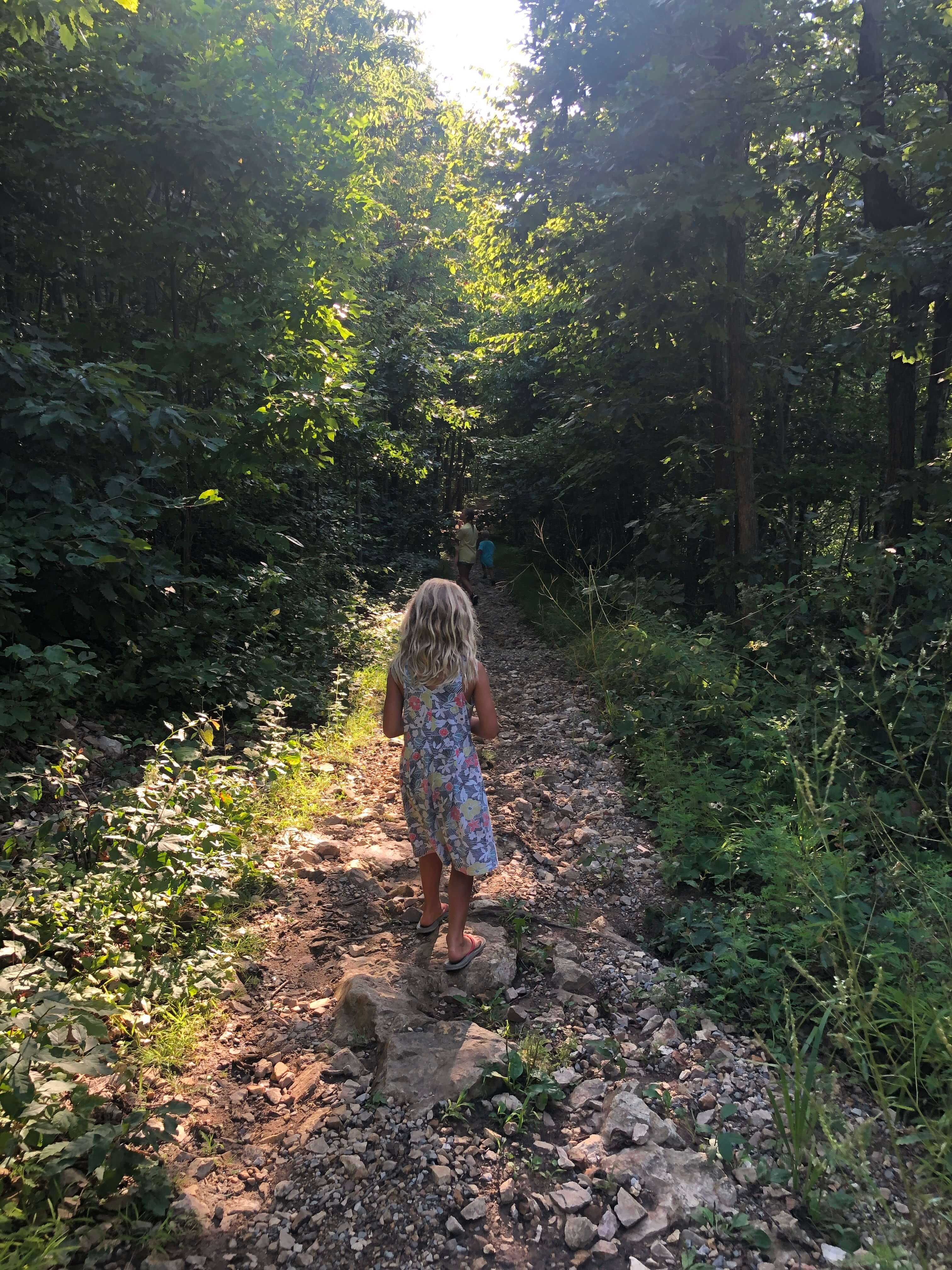 a young girl wanders down a rocky trail