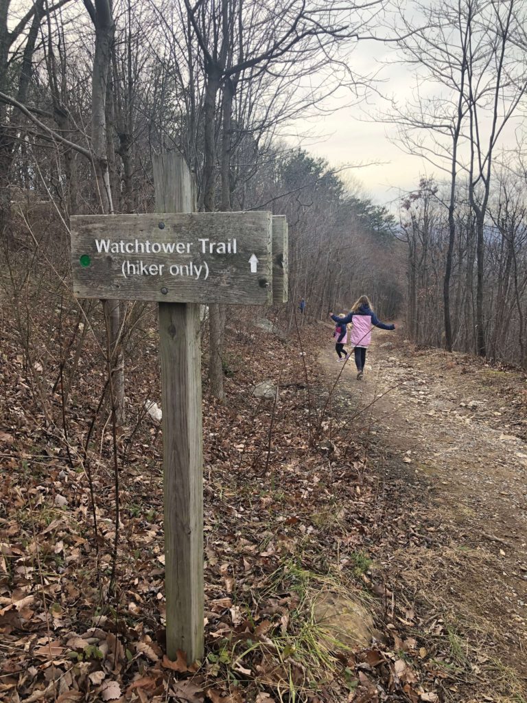 two children hop down a trail while a sign reading "Watchtower Trail (hiker only)" is in the foreground