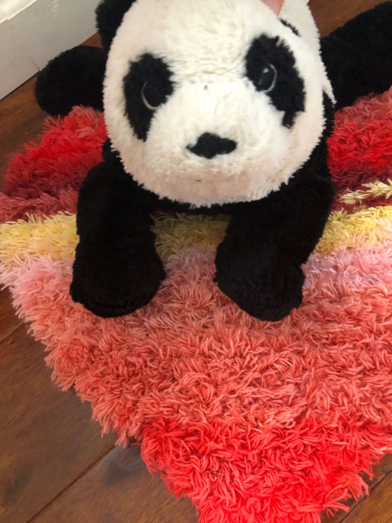 a panda takes a break on the Cordata Heart Rug