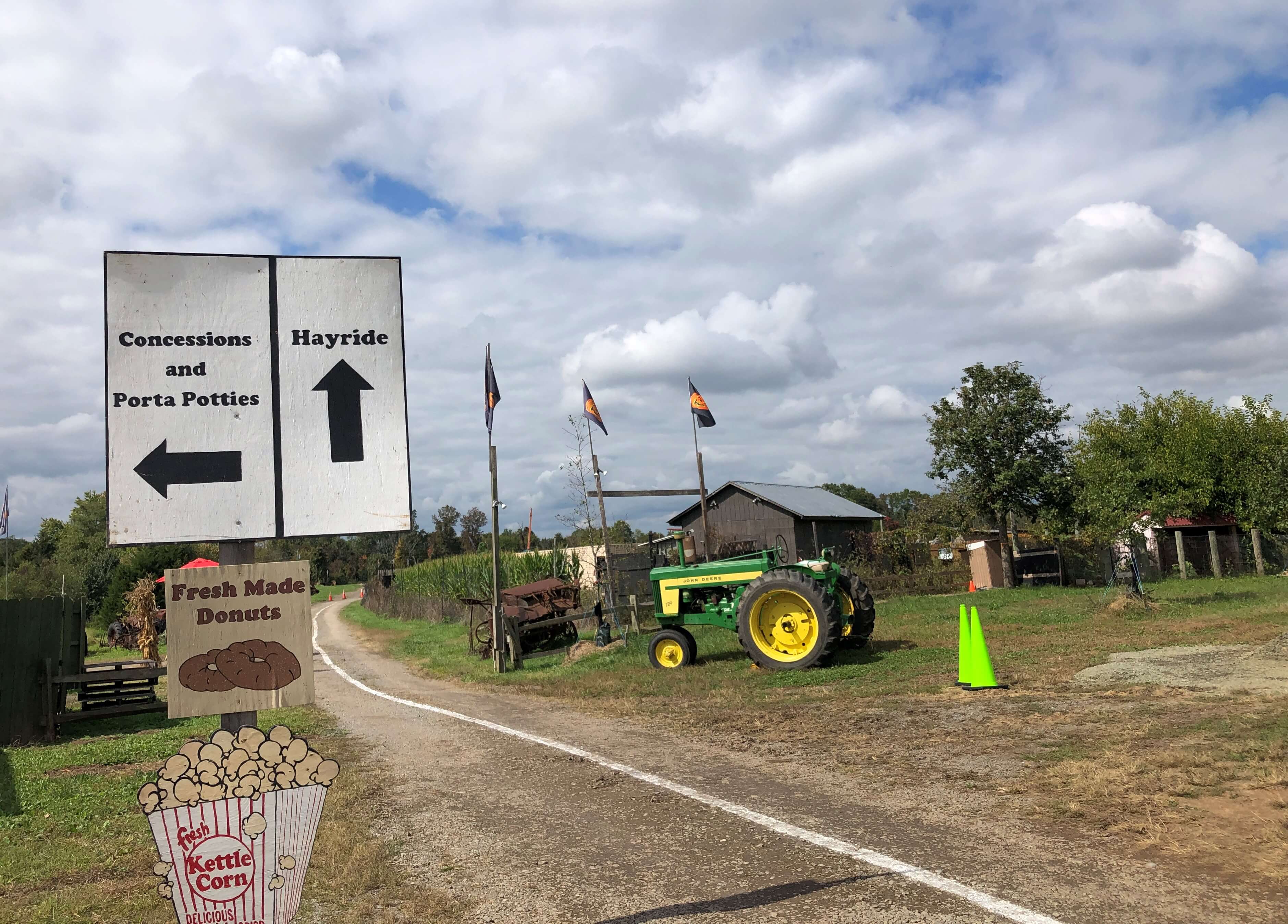 a single white line marks the path for drivers while signs point the way to kettle corn, donuts, hayrides, and porta potties