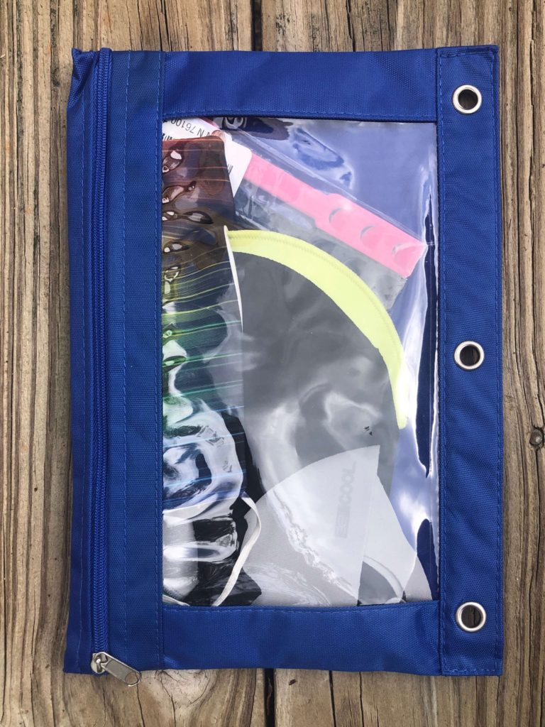 a clear plastic pencil case full of masks and mask clips