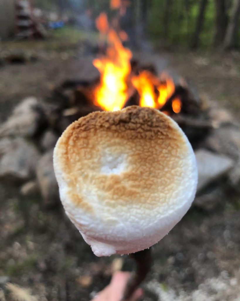 a perfectly toasted marshmallow in front of a campfire