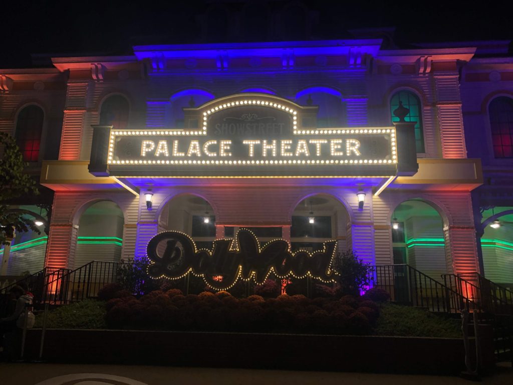 at night, the exterior of the Showstreet Palace Theatre at Dollywood shines, lined with white bulbs and focused light of all colors