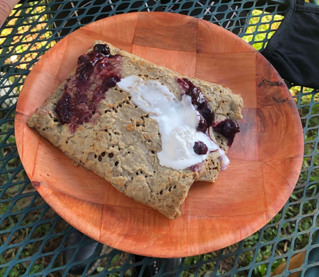 a crepe with berries and coconut cream waits to be eaten