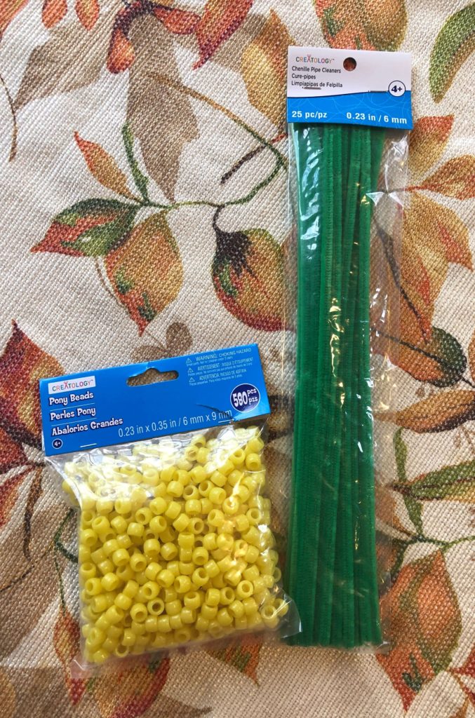 a pack of pony beads and chenille stems on an autumn tablecloth