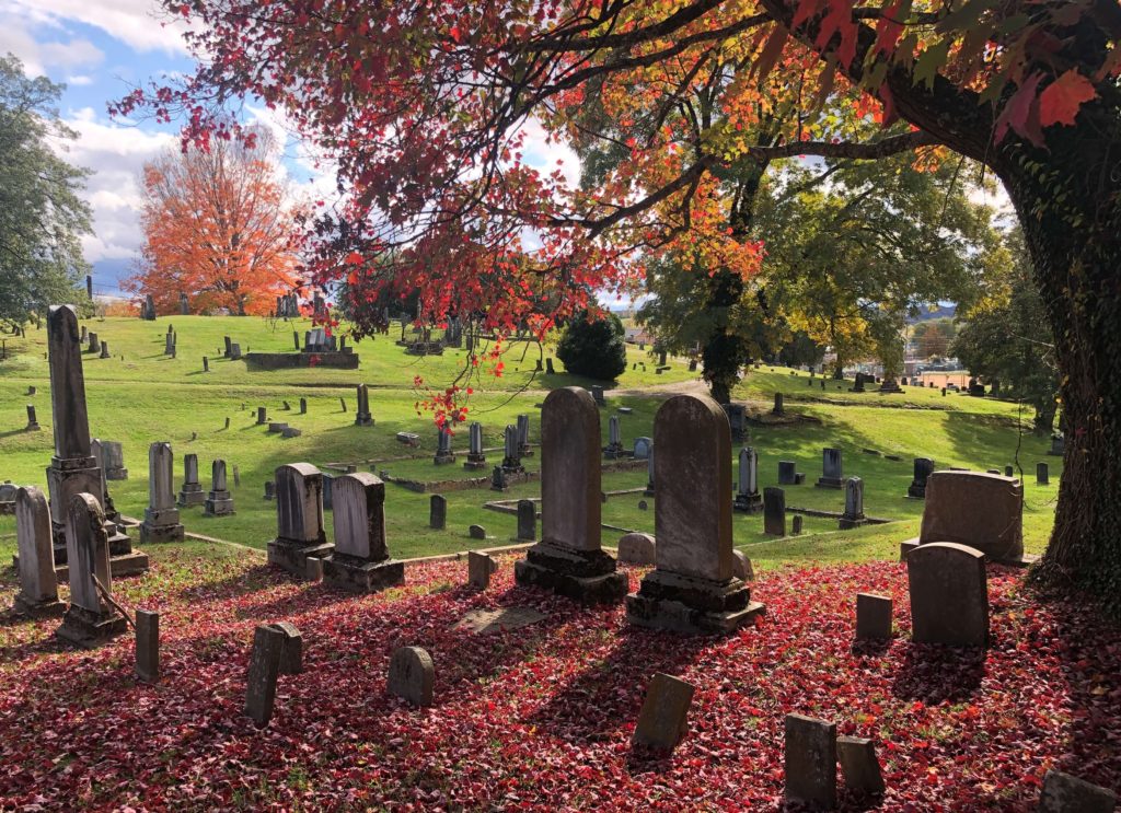Pairs of matching headstones cast shadows under a tree shedding its leaves at Sinking Spring Cemetery in Abingdon, Virginia