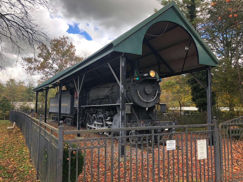 a wrought-iron fence surrounds a locomotive with a smiling face