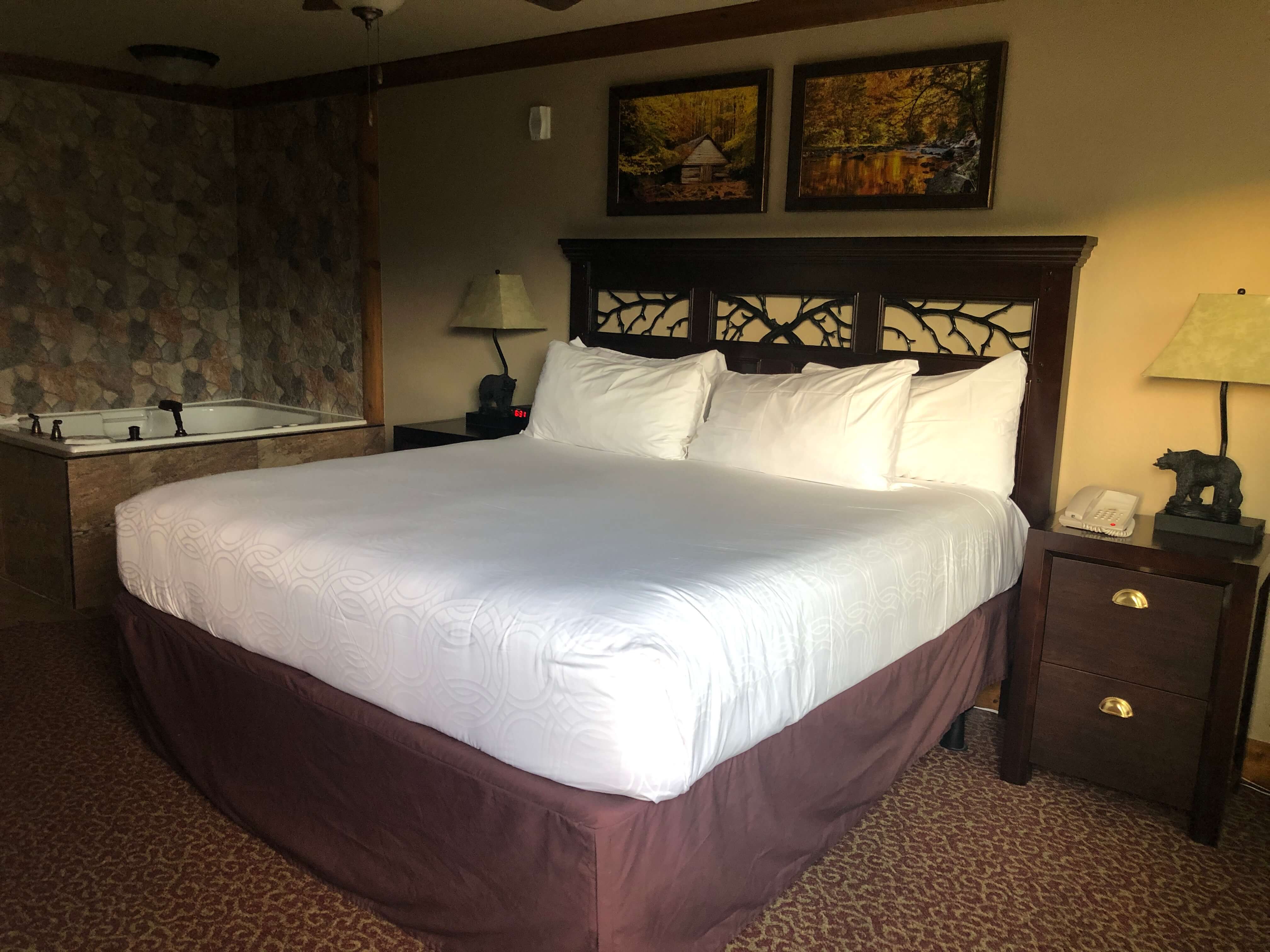 a king-sized bed in a lodge-themed room with a large jacuzzi tub