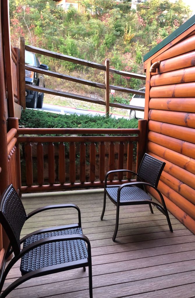 two chairs on a small patio outlooking a parking lot