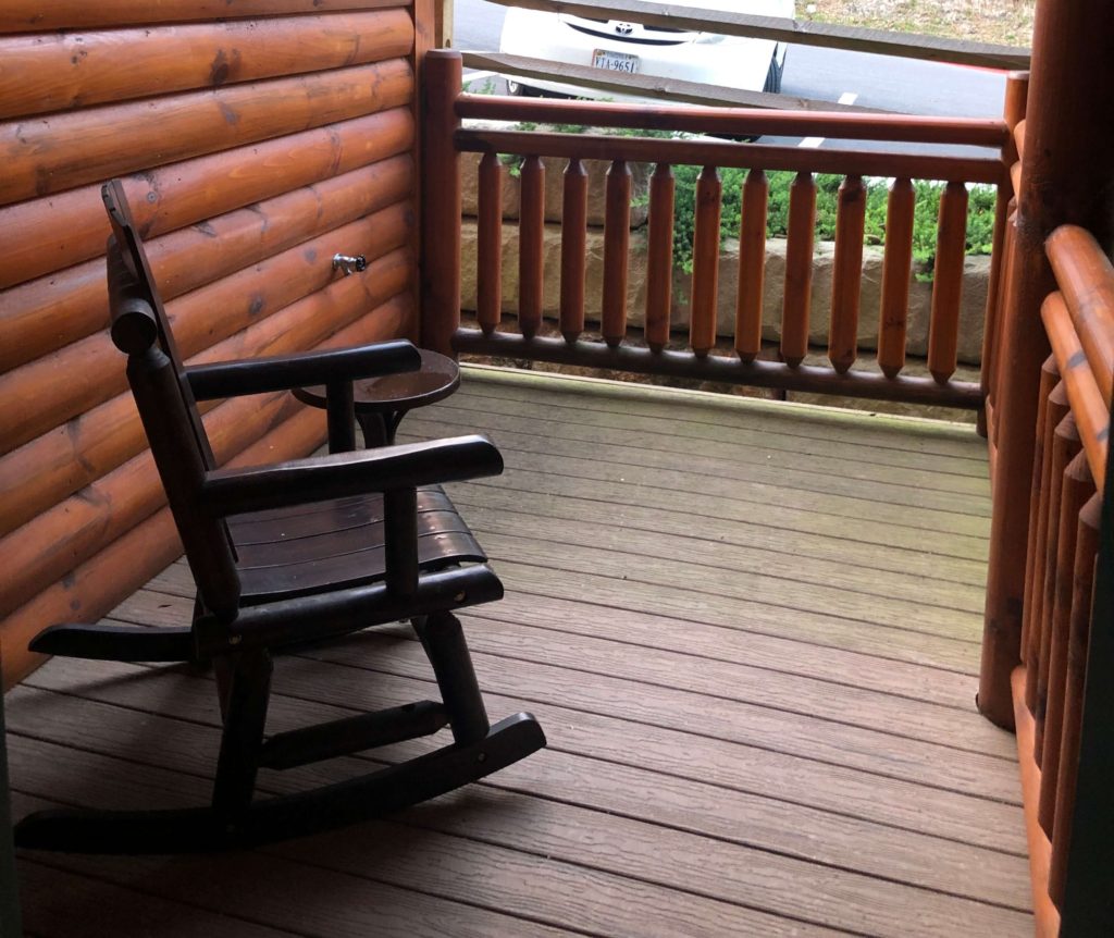 a rocking chair on a small patio overlooking a parking lot
