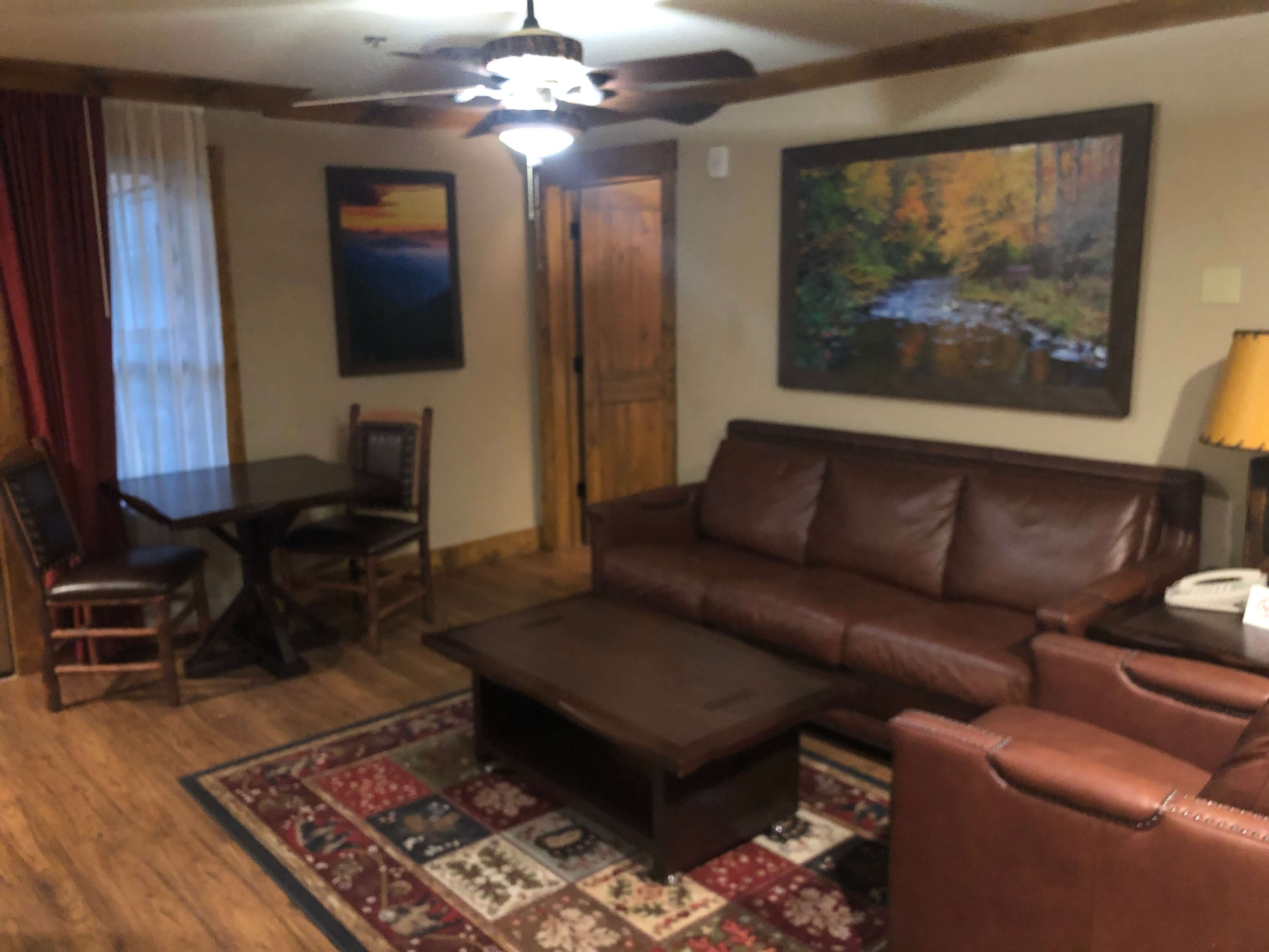 a couch and chair flank a coffee table next to a dining table with two chairs