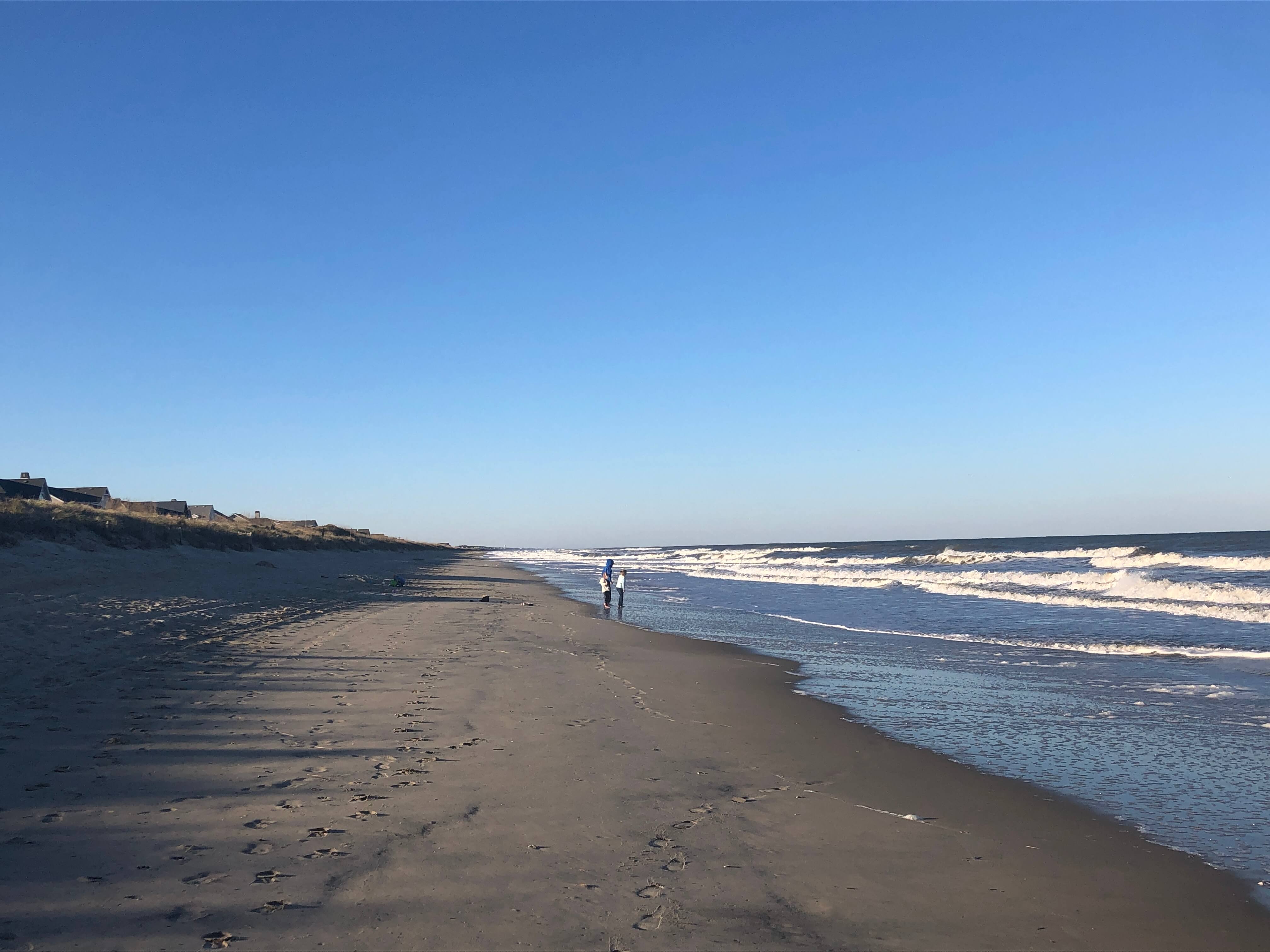 three children in sweatshirts watch the tide go out in Duck, North Carolina