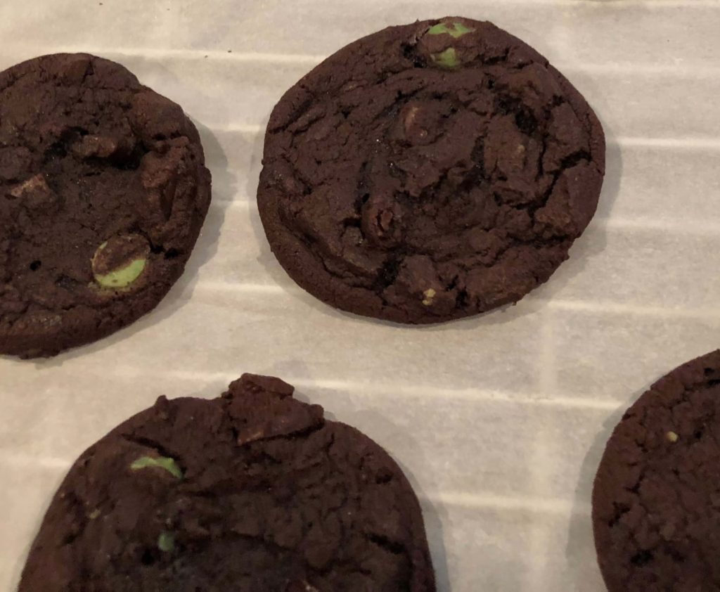 chocolate cookies with green chips cool on a rack