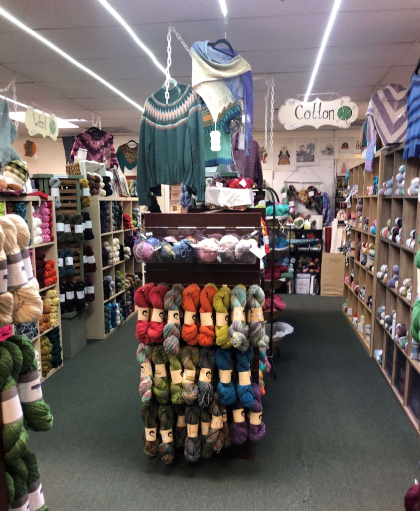 hanks of yarn line shelves under a hand-painted sign that reads "Cotton"