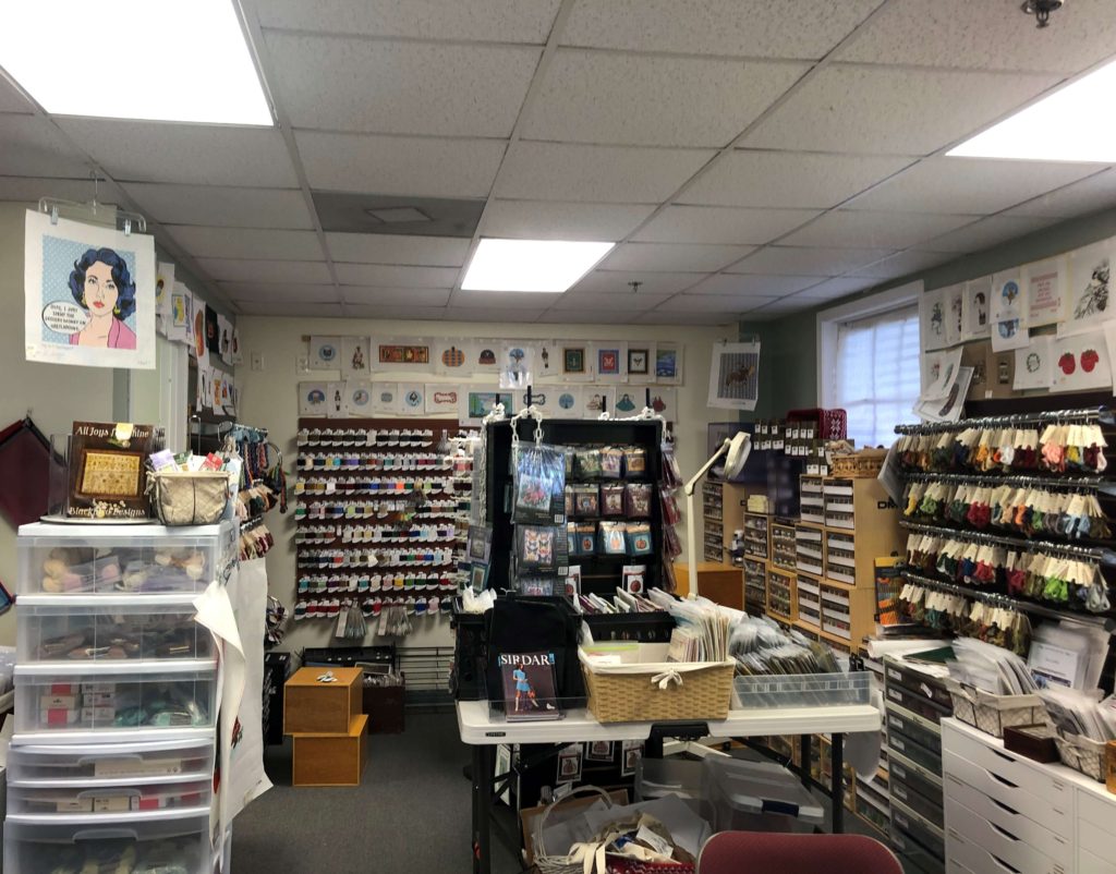 a shop corner full of needlepoint accessories, books, and thread