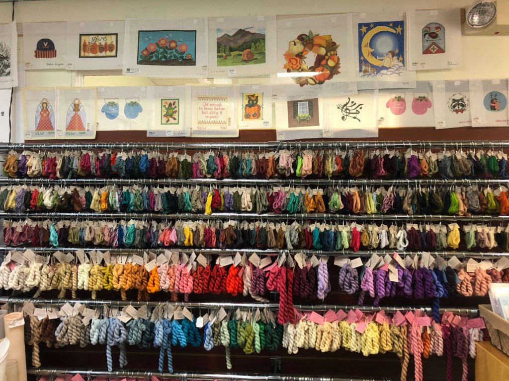 a wall of hand-painted needlepoint canvases and thread