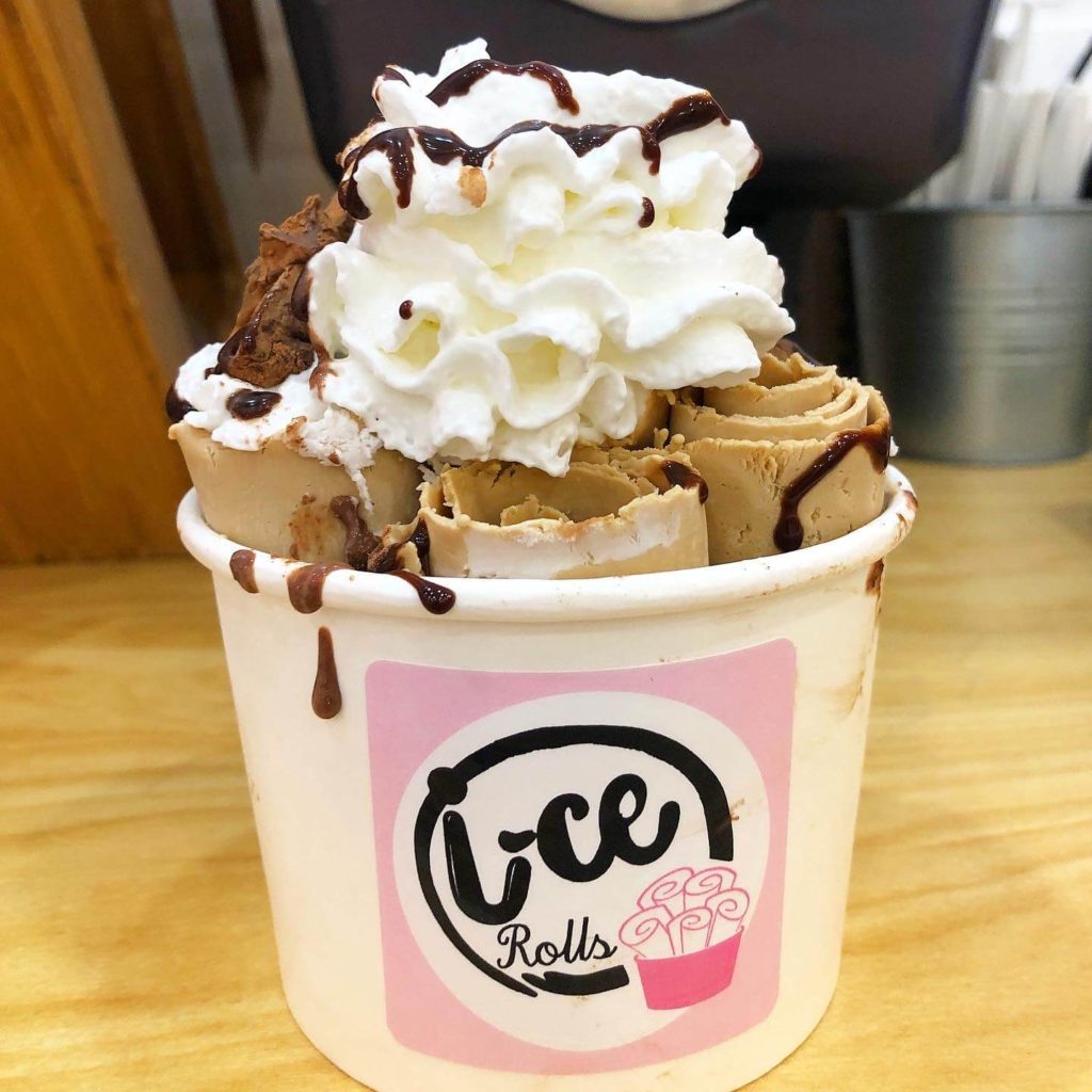 rolled coffee ice cream with chocolate drizzle, cocoa-dusted truffles, and whipped cream topping