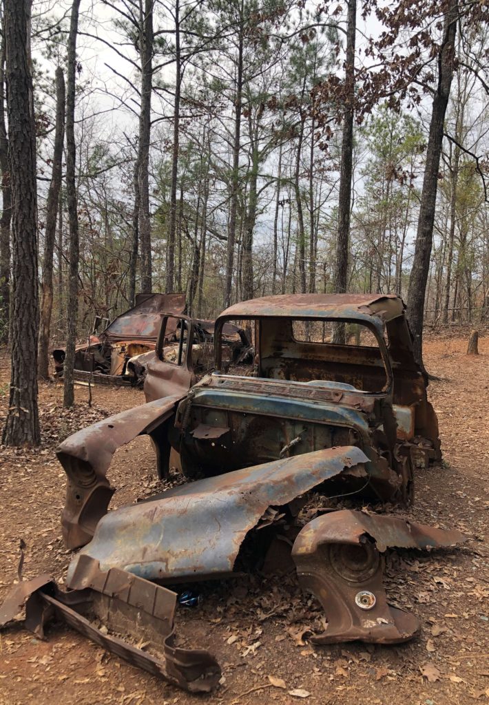an antique car is broken into pieces in the middle of a forest