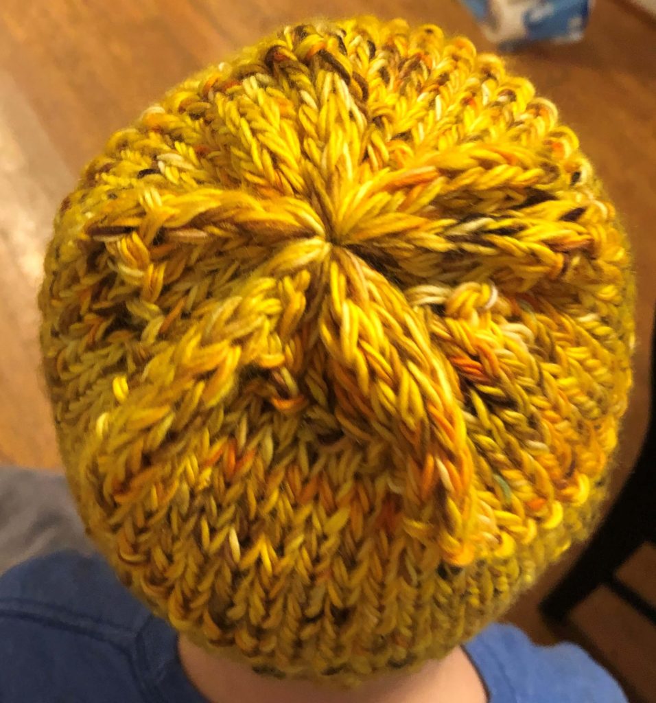 a top-down view of the Purl Swirl hat shows a star-shaped cinch pattern at the crown