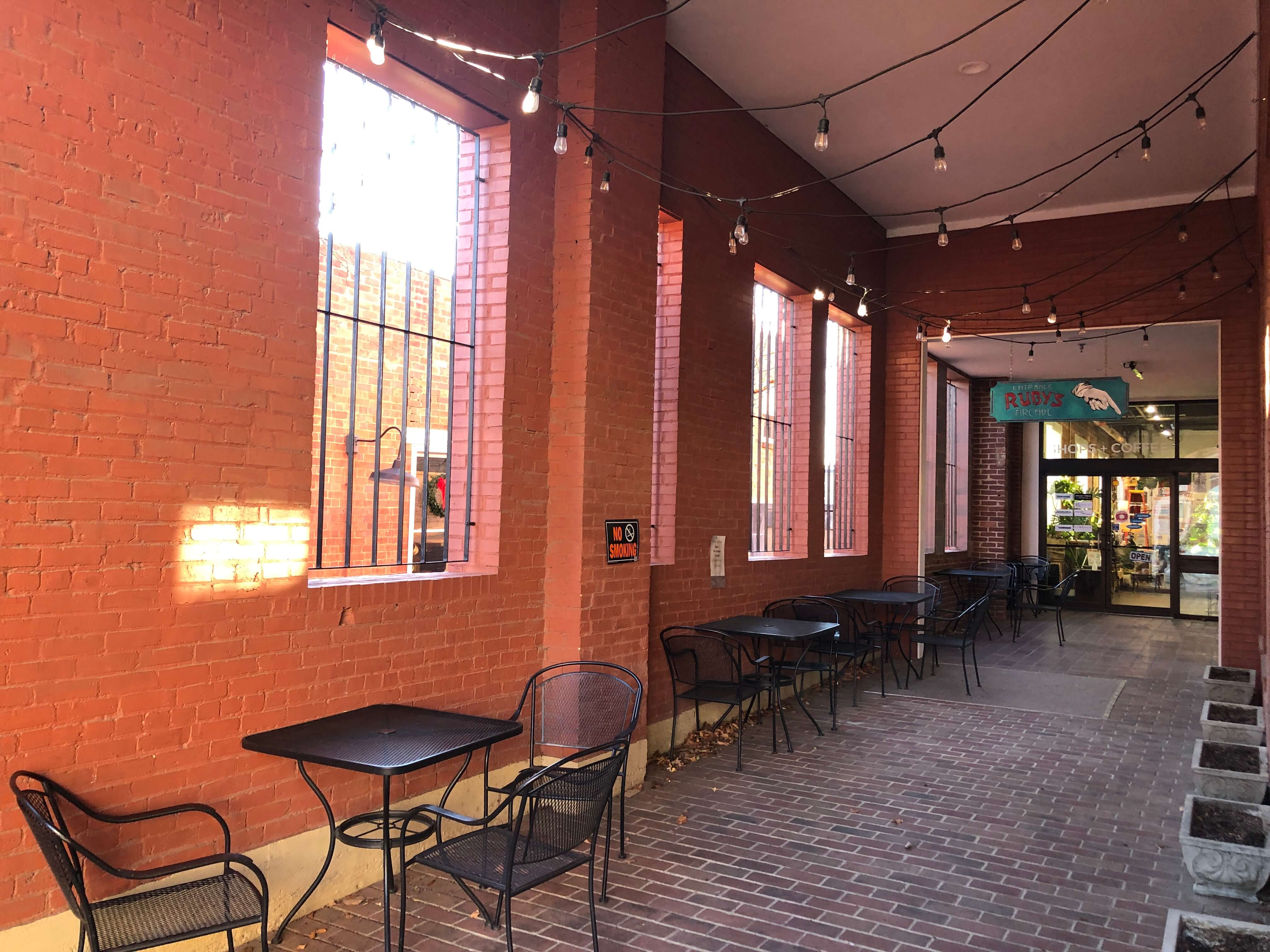 a brick entryway is flanked with wrought iron seating and cement planters and lit with hanging lights