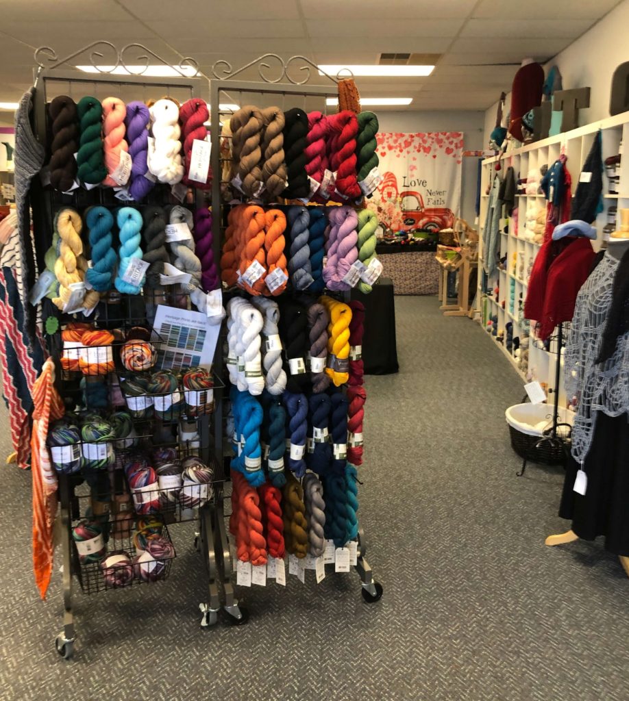 hanks of yarn hang from pegs in a yarn shop