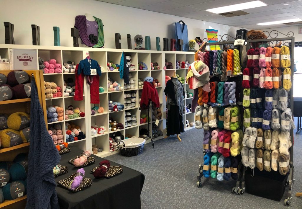 large block letters spell out KNIT and CROCHET on top of shelves of yarn