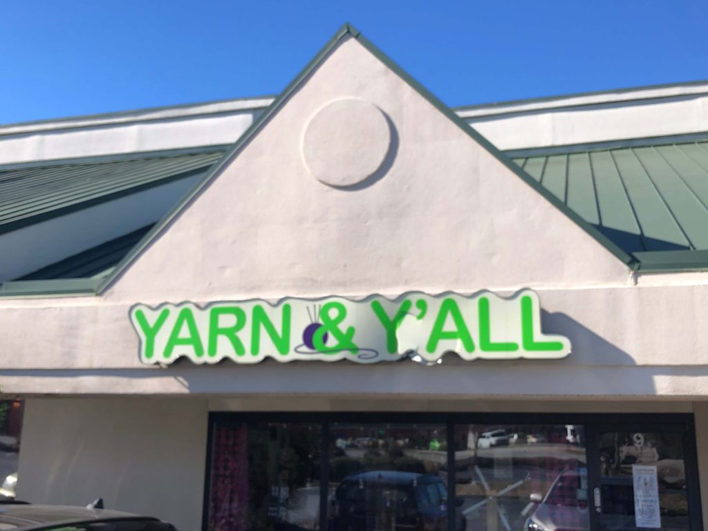 the exterior to Yarn & Y'all features a sign with yarn wrapped through the ampersand in the shop name