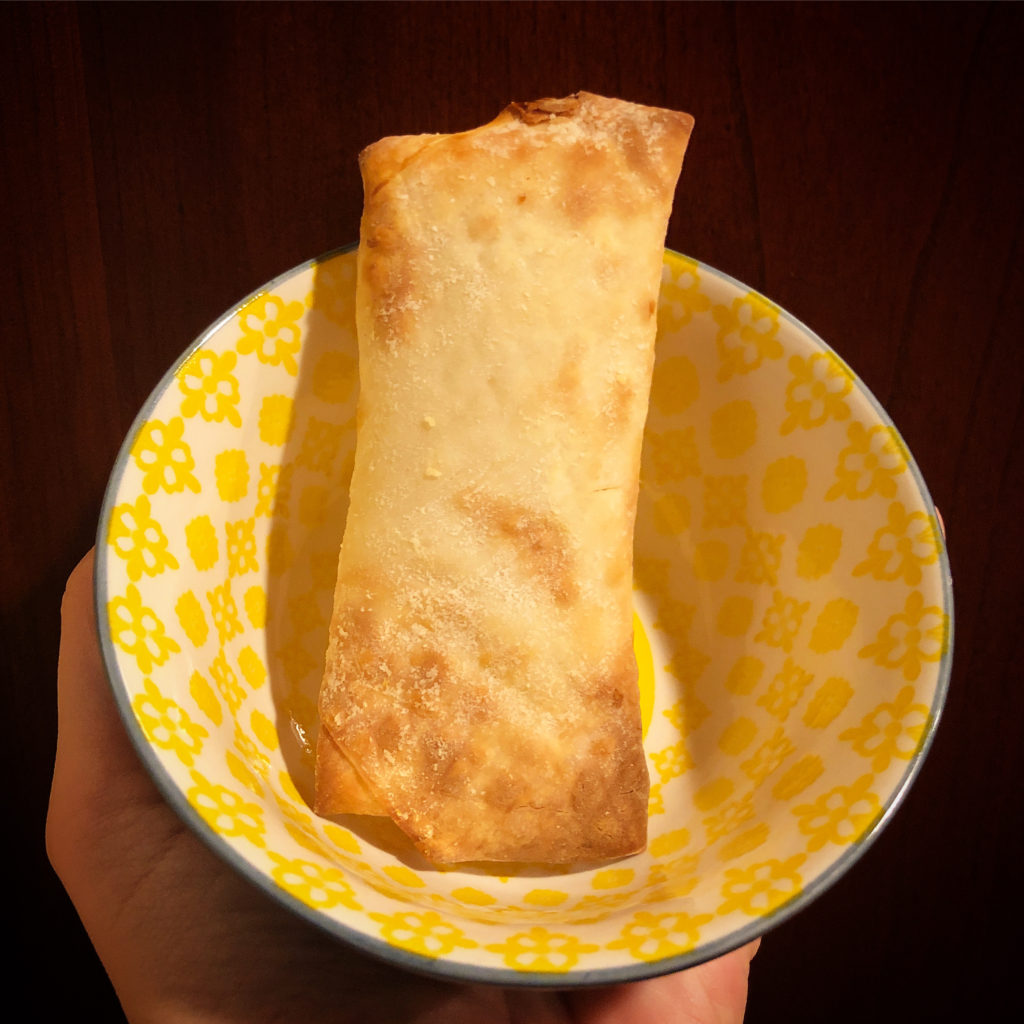 a cream cheese pineapple spring roll, hot out of the air fryer, in a bowl