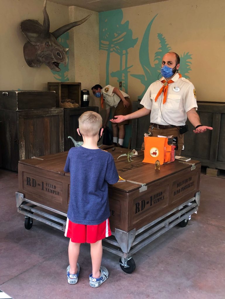 a Wilderness Explorer badge guide explains to three children how tooth shape in fossils explains how we know what dinosaurs ate