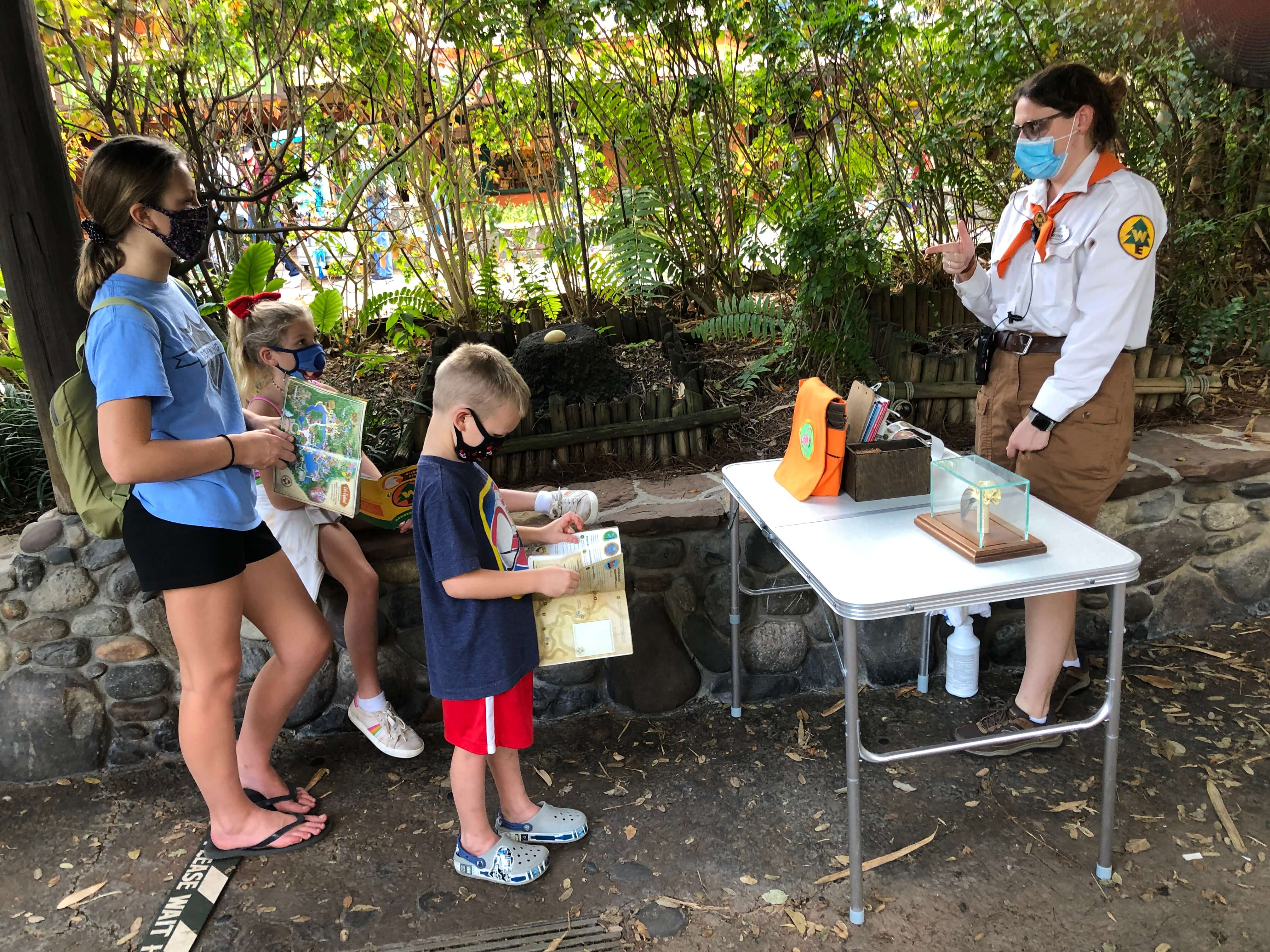 a Wilderness Explorer badge guide explains to three children how human activity impacts animals