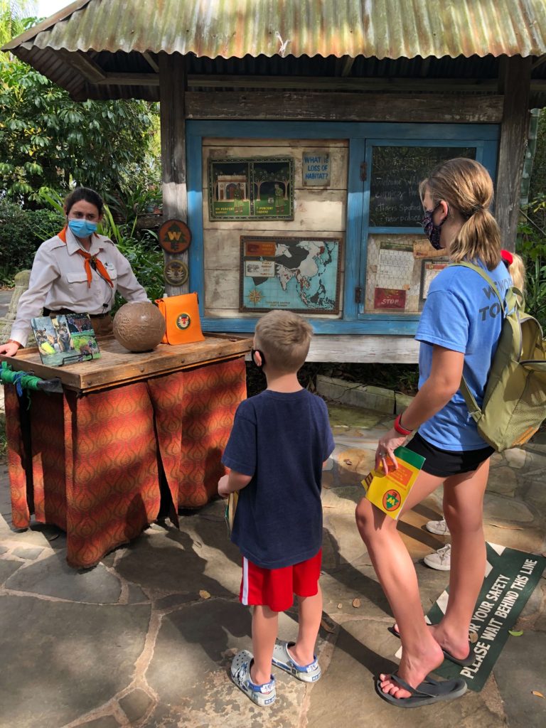 a Wilderness Explorer badge guide explains to three children how animals at Animal Kingdom enjoy playtime