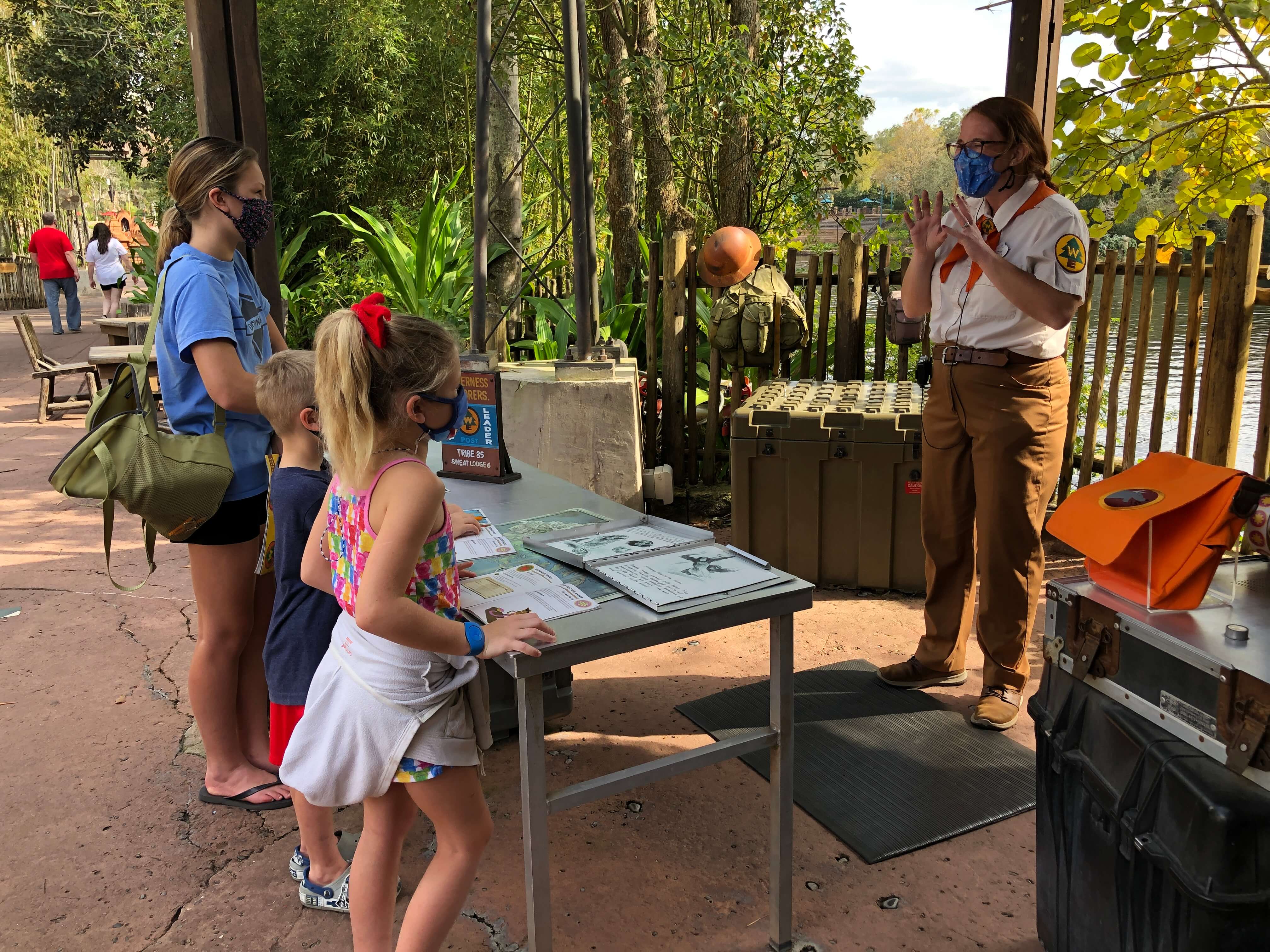 a Wilderness Explorer badge guide explains to three children how human activity impacts animals
