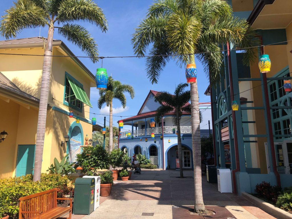 paper lanterns hang over the crossroads between several market buildings and palm trees