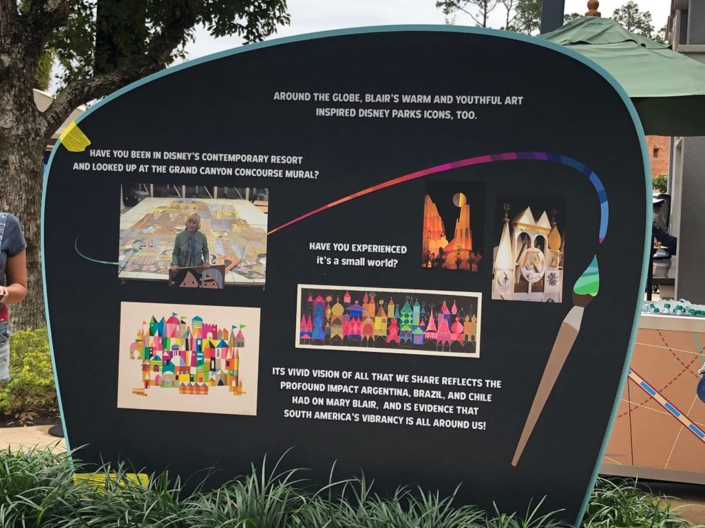 A sign reads, "Around the globe, Blair's warm and youthful art inspired Disney Parks icons, too."