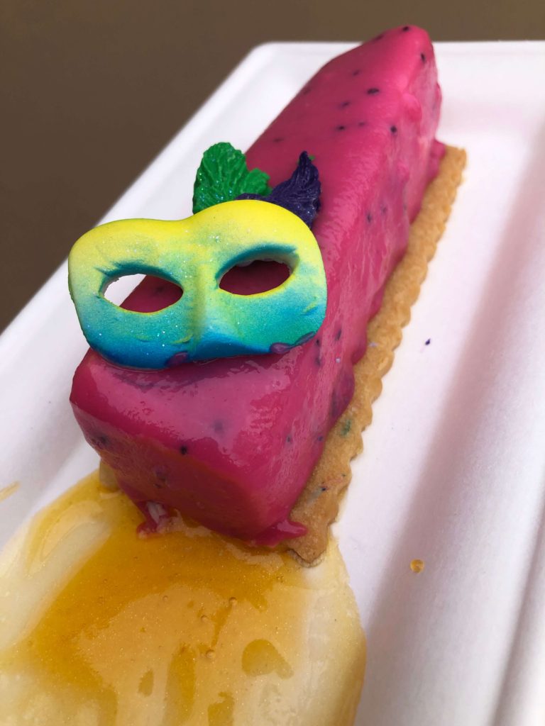 a candied drama mask decorates a dish of passion fruit mousse