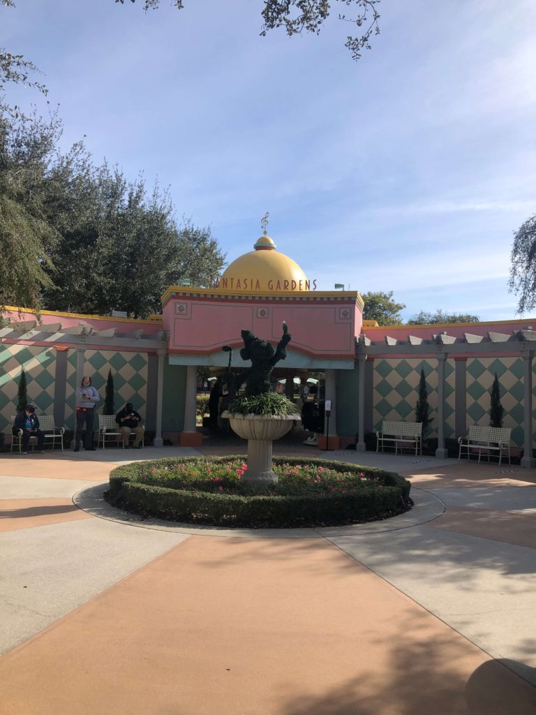 the exterior of Fantasia Gardens mini golf features a sign, elaborate tilework, and a shrubbery shaped like Sorcerer Mickey