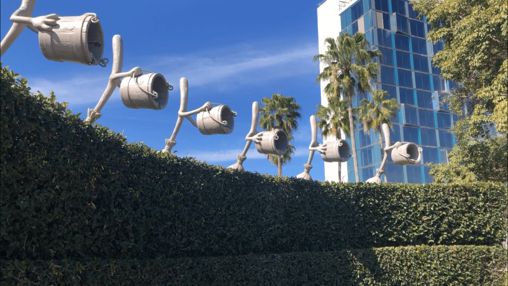 enchanted mop statues dump buckets of water over a hedge